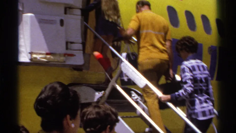 In La Paz, Mexico in 1974, travelers board a yellow commercial airplane using mobile stairs while a crew member stands near the door.