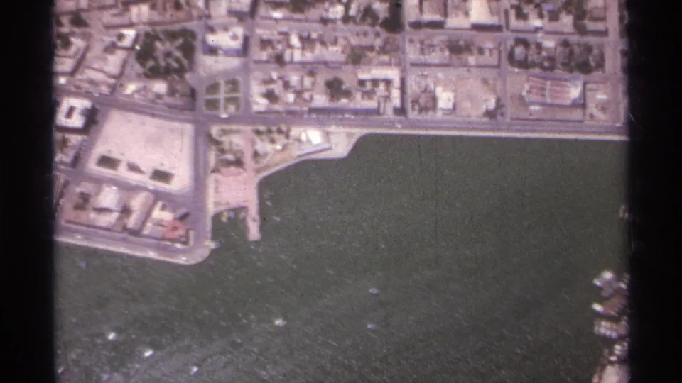 1974 La Paz, Mexico aerial view with low-rise coastal blocks, a waterfront road, dark harbor water, and small boats.