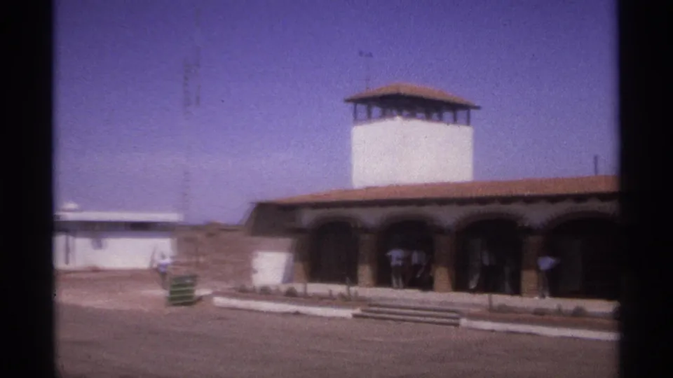 1974 La Paz, Mexico 8mm still showing the towered building from closer range, with arched bays, steps, and people at the shaded entrance.