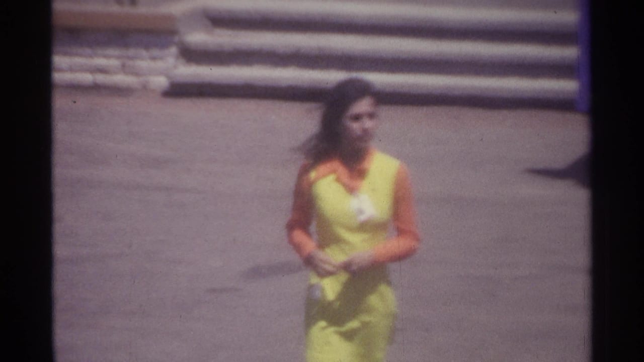 Closer view of the woman in uniform walking on pavement with steps behind her.