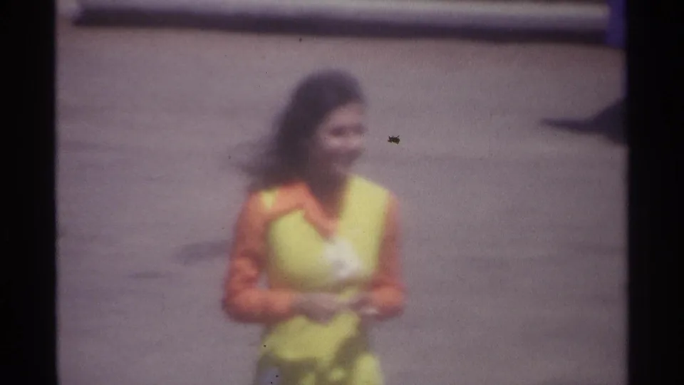 Soft 8mm close view from La Paz in 1974 showing the uniformed woman smiling as she nears the camera.