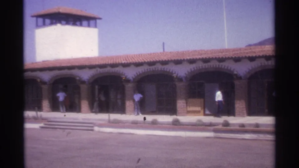 1974 La Paz frame of a long arched building and several pedestrians across a broad paved foreground.