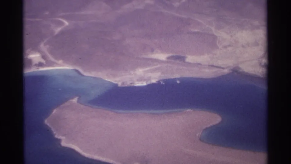 La Paz-area aerial 8mm frame with sandy landforms, blue coastal water, and visible scan borders from the film strip.