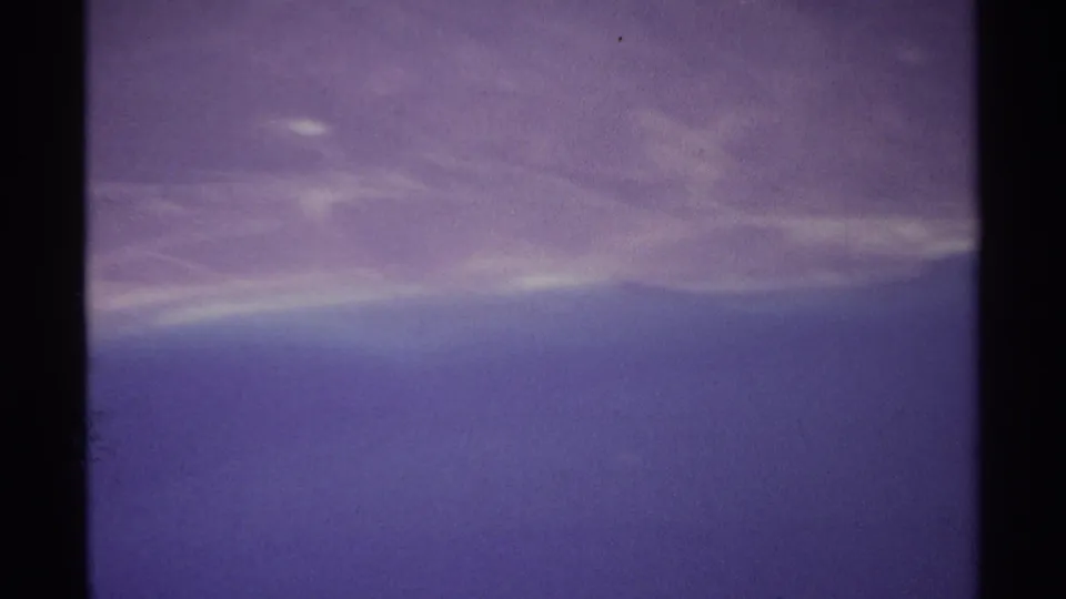 Soft 8mm aerial view near La Paz, Mexico, with open ocean in the foreground and a faint arid shoreline across the upper frame.