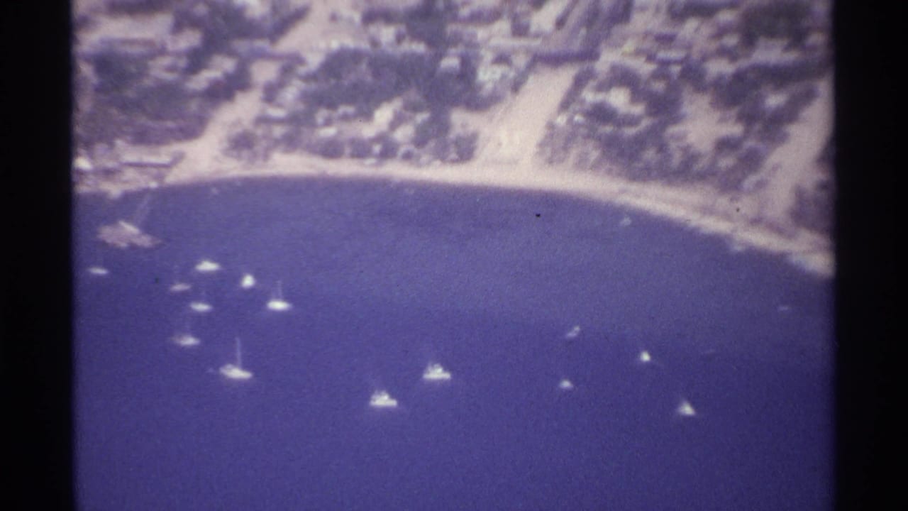 Aerial coastal view with boats in the bay and buildings along the shore.