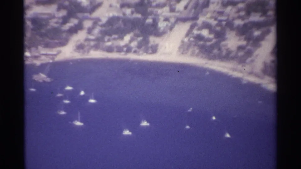 1974 La Paz, Mexico aerial frame with small boats on deep blue water and a built-up shoreline beyond.