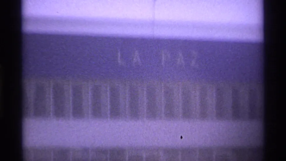 1974 La Paz, Mexico frame with faint facade lettering reading LA PAZ, seen in soft focus through dark vertical bars.