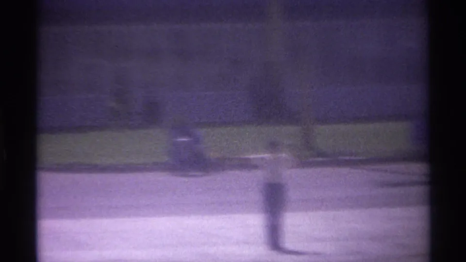 Home-movie frame from the La Paz airport clip with soft focus, dark film borders, pale tarmac, and distant indistinct ground equipment.