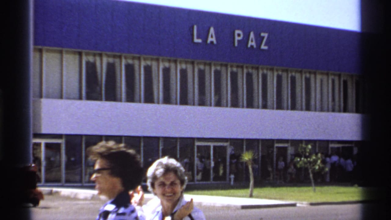 Two women near the La Paz terminal entrance, with people gathered by the doors.
