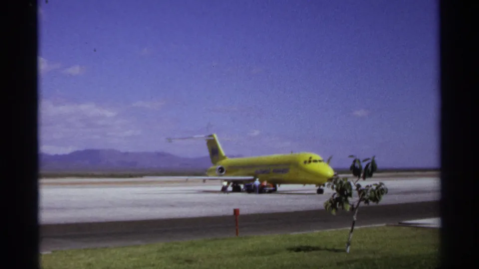 Wide La Paz airport view from 1974 with a yellow Kuwait Airways jet parked on the tarmac and small figures nearby.