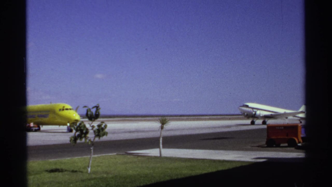 Yellow plane near the left and white propeller aircraft on the right side of the tarmac.