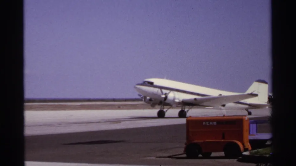 1974 La Paz airport footage showing the propeller airliner nearer to the camera with the orange Aero Mexico vehicle below it.
