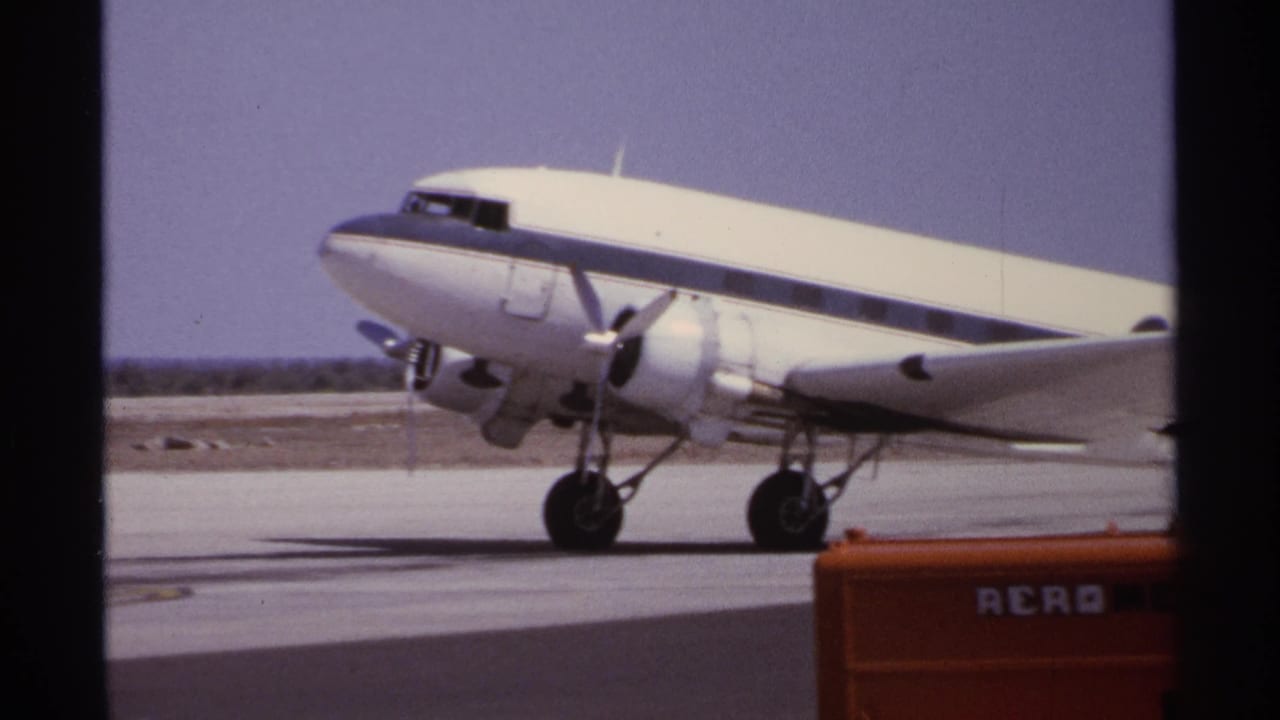 Twin-prop aircraft crossing the tarmac near orange ground equipment.