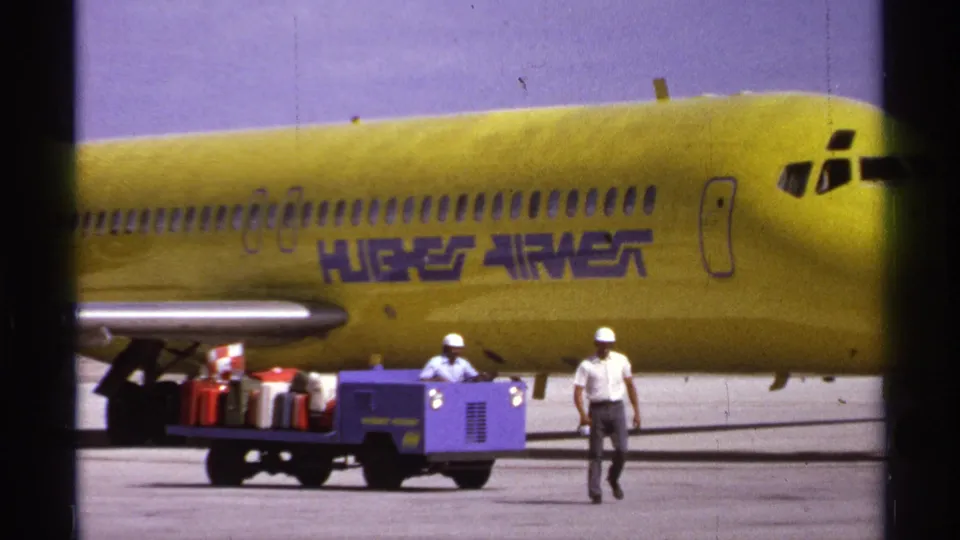The final frame shows the forward section of the yellow Hughes Airwest aircraft at La Paz, with hard-hatted ground crew and baggage equipment below.