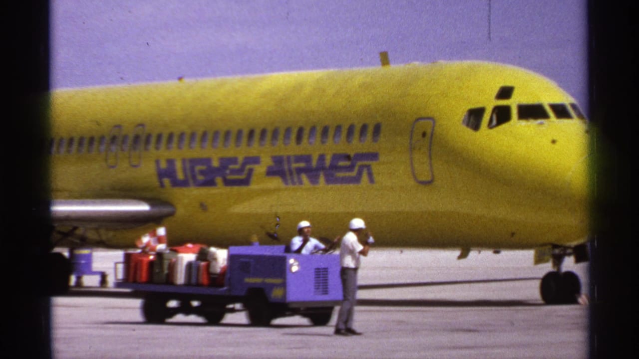 Yellow Hughes Airwest aircraft beside a luggage cart and ground crew on the tarmac.