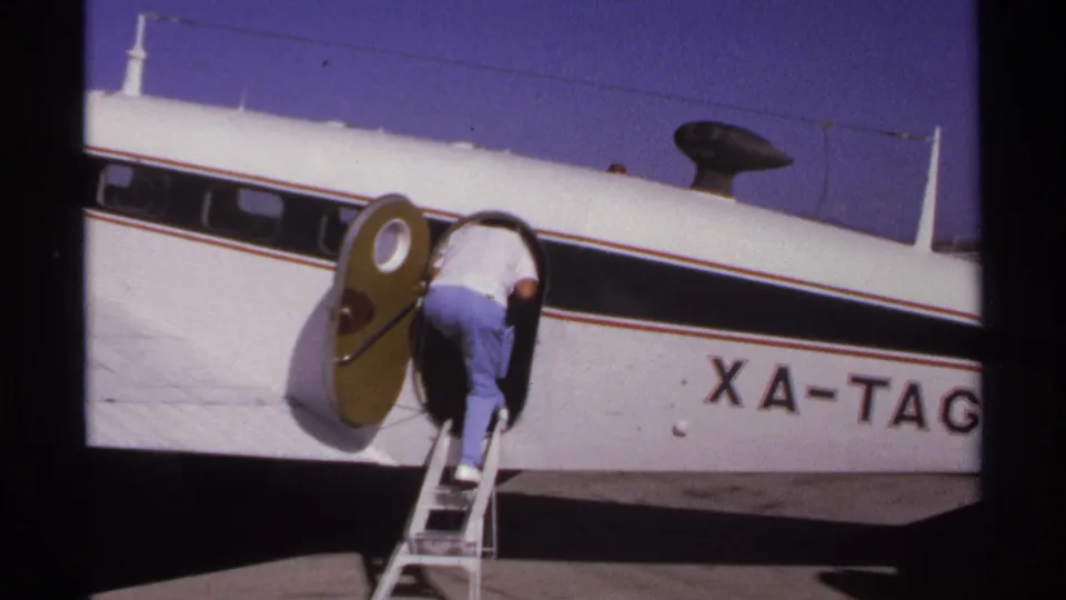 The boarding man leans into the oval doorway of the small white plane in La Paz, Mexico, 1974.