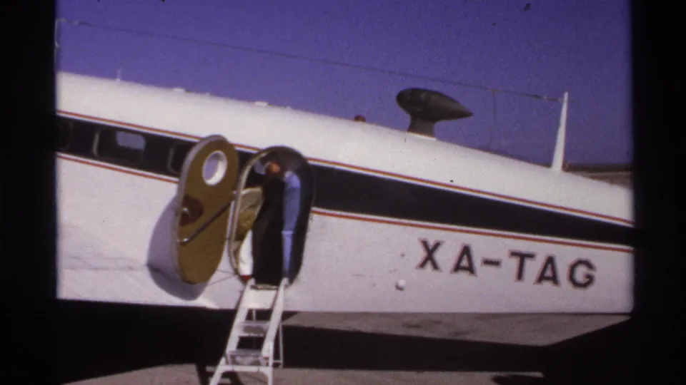 A traveler is partly inside the doorway of the small commuter plane, with registration letters visible on the fuselage.