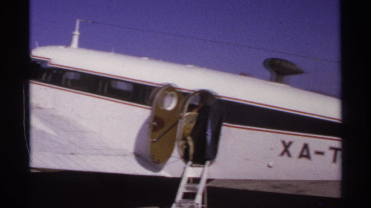 White propeller aircraft with partial XA-TAG markings and portable ladder near the fuselage.