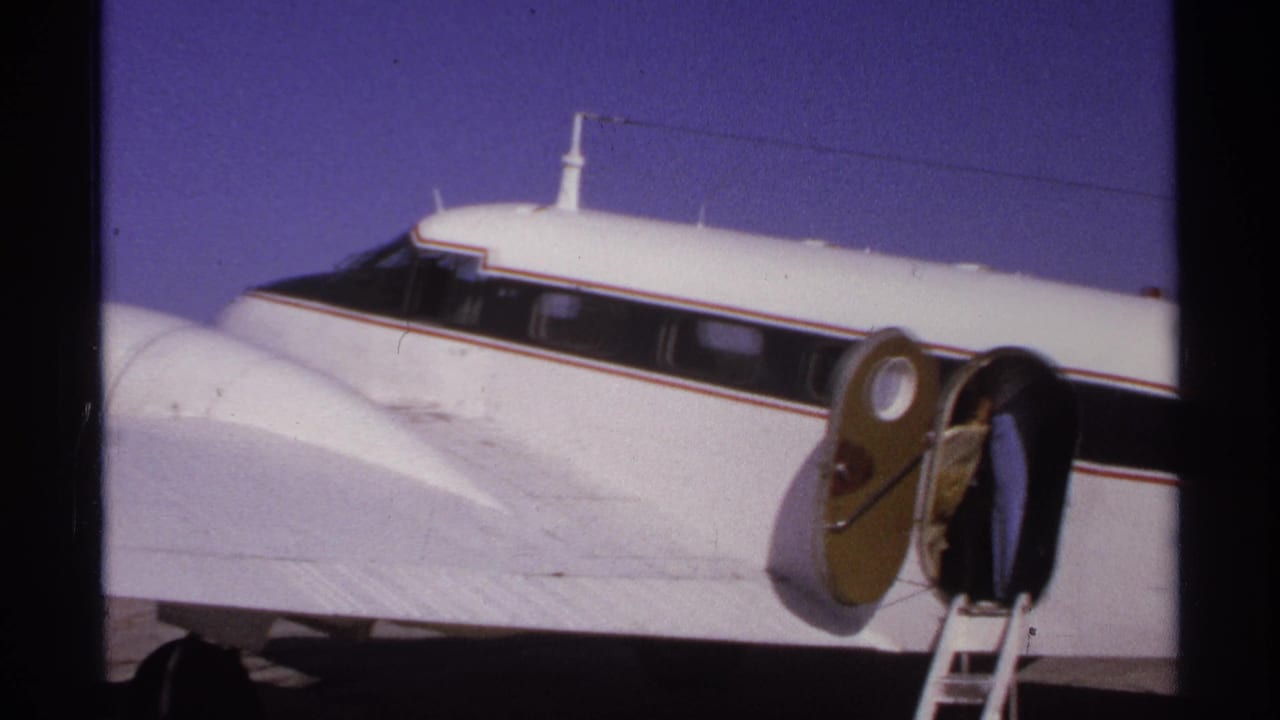 Close view of a white propeller aircraft nose, side windows, oval door, and ladder.