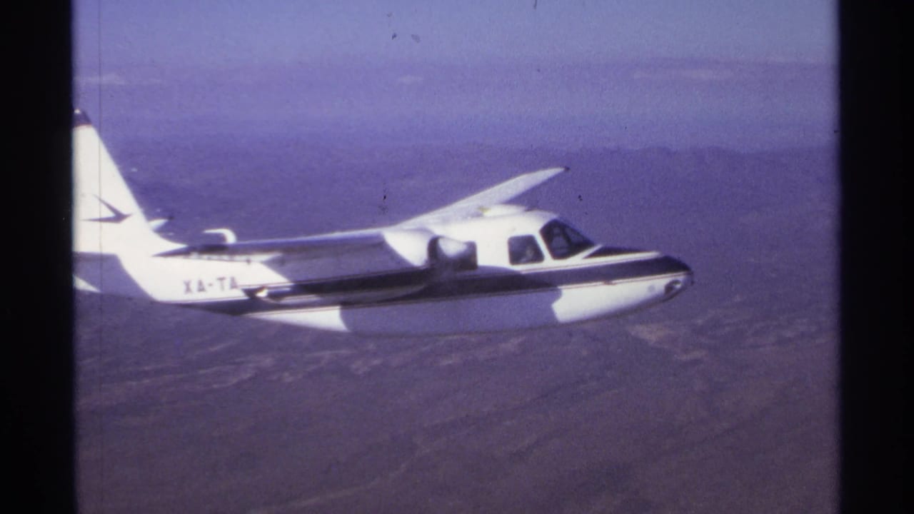 Small propeller plane centered against hazy sky and dry land below.