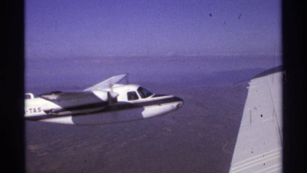 Small aircraft marked XA-TAS flying near an aircraft wing over water.