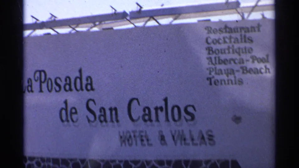 1975 Guaymas 8mm frame showing the La Posada de San Carlos Hotel and Villas sign with bilingual amenities listed.