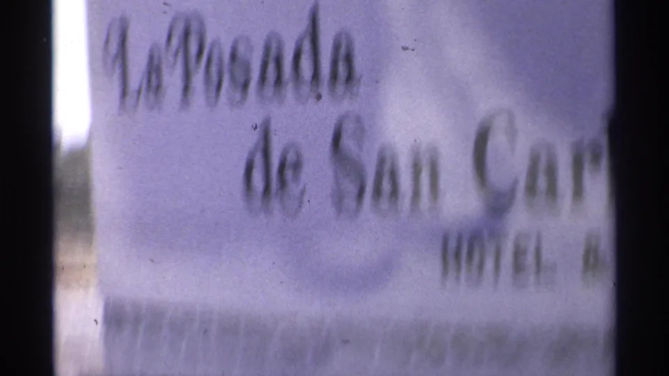 Blurred 1975 8mm frame as the handheld camera moves across the La Posada de San Carlos hotel sign.