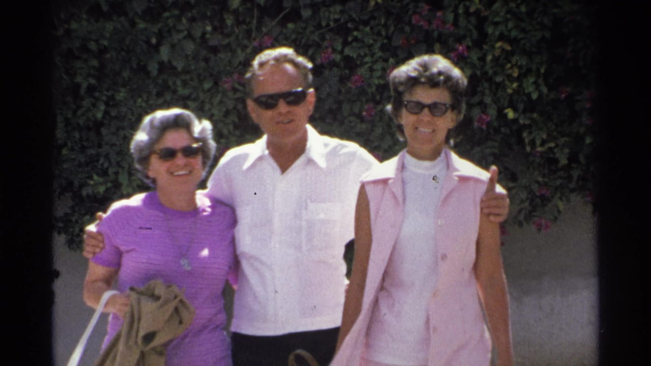 In the 1975 Guaymas home movie, three adults in sunglasses stand arm in arm in front of dense greenery.