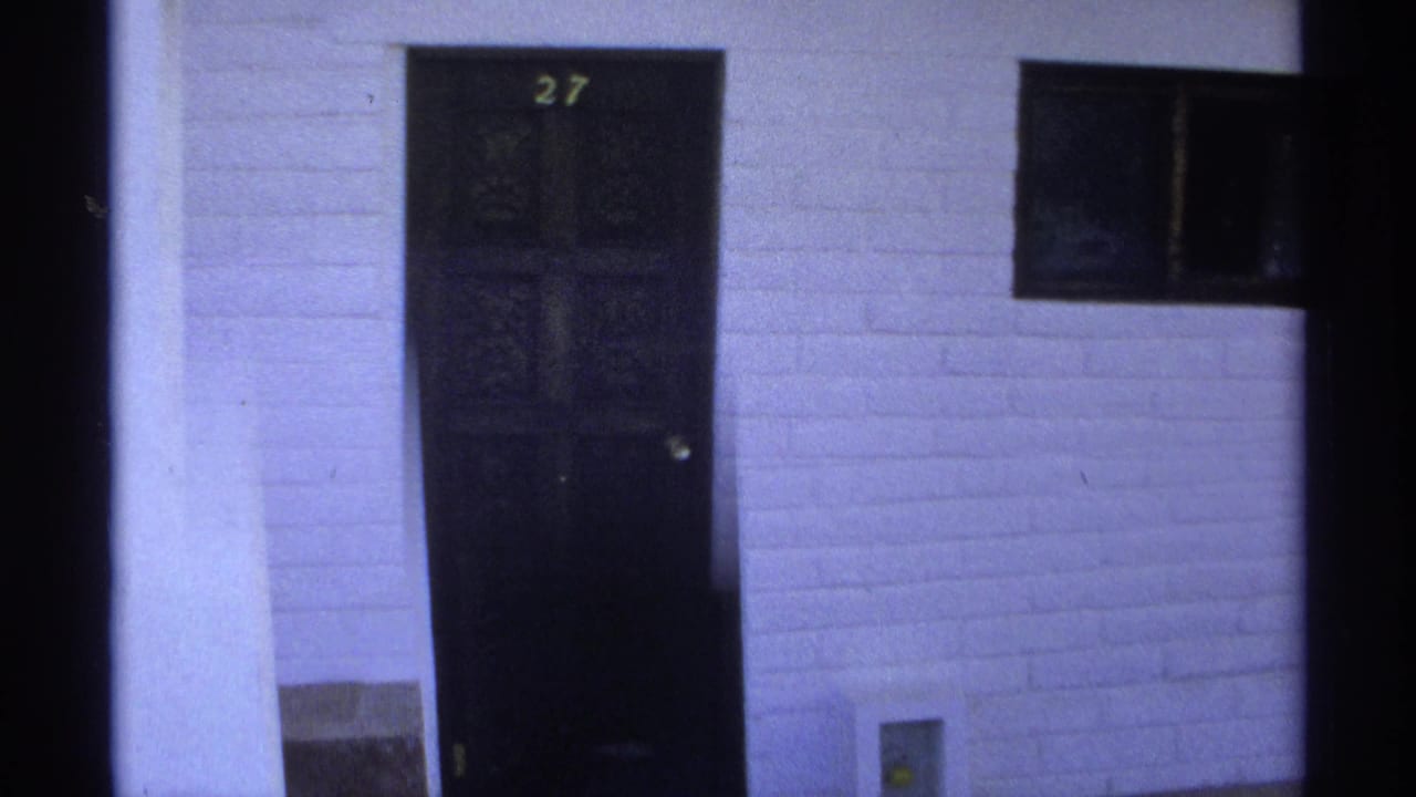 Closed dark door marked 27 with a window and white wall nearby.