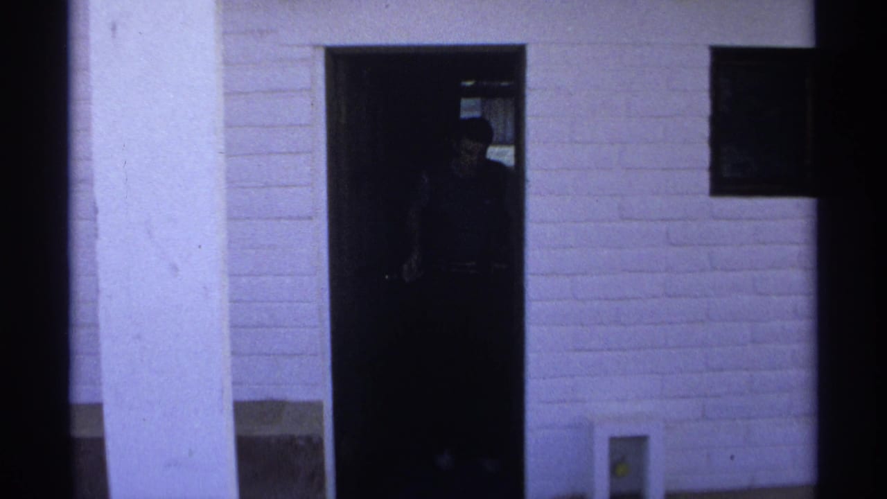 A person appears in shadow at the open apartment doorway in 1975 Guaymas home-movie footage.