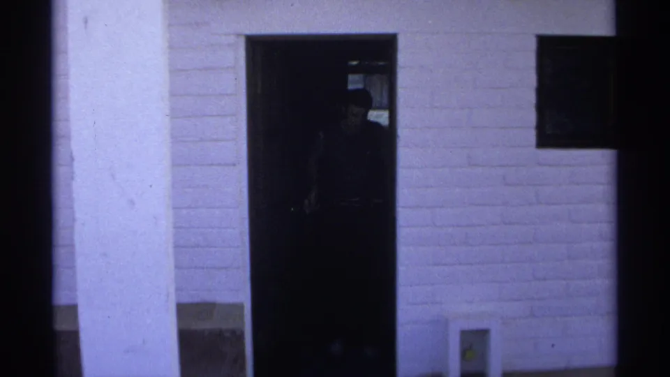 A person appears in shadow at the open apartment doorway in 1975 Guaymas home-movie footage.