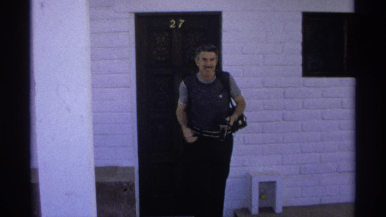 Man faces forward near the same numbered doorway while holding camera equipment.