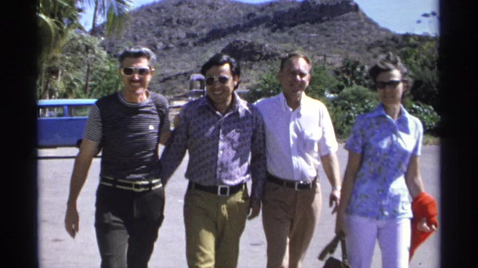 Close 8mm frame from Guaymas, Mexico, showing four adults walking toward the camera in bright sun with hillside and palms behind them.