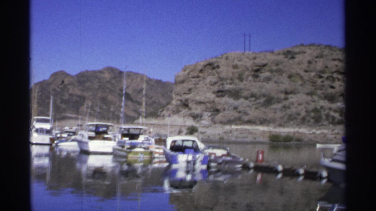 Small boats docked in calm water below a rocky hillside.
