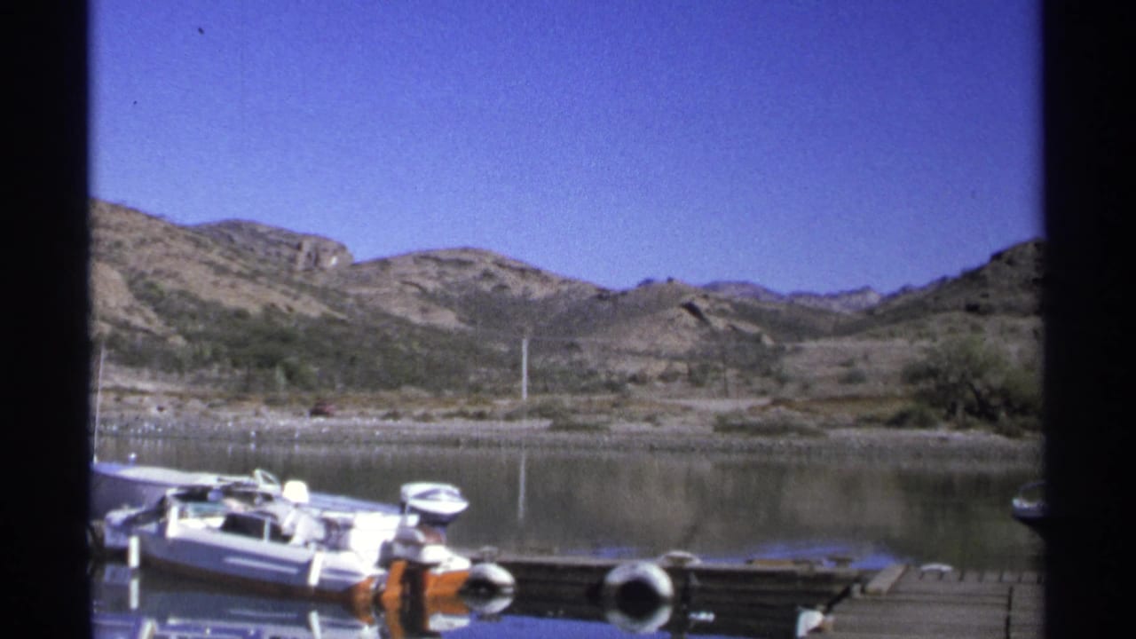 Moored boats and dock edge sit before still water and low desert hills.