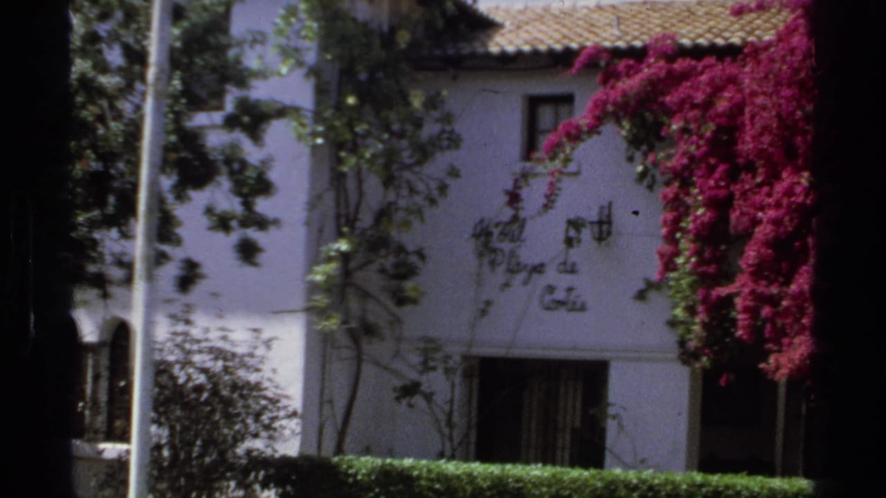 White stucco hotel facade with terracotta roof, vines, and magenta bougainvillea.