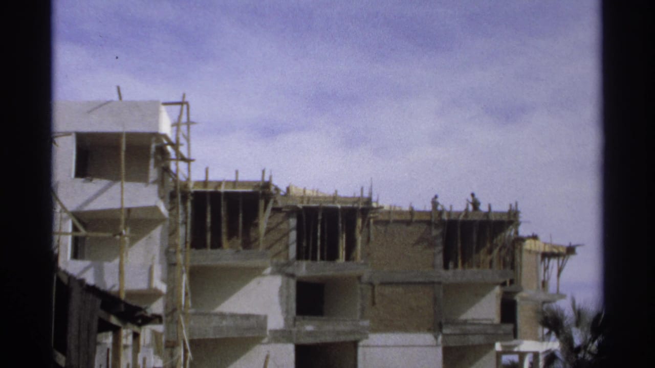 Construction site with workers on an upper floor and exposed framing.