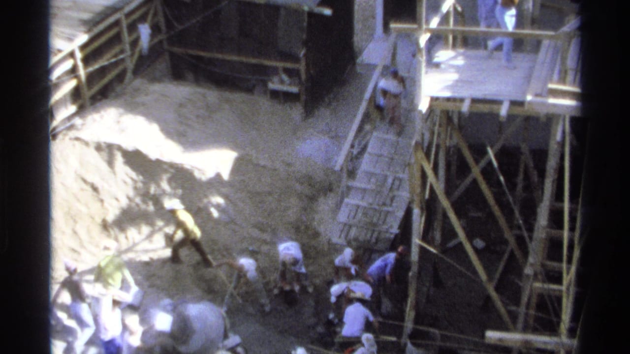 1975 Guaymas, Mexico 8mm frame showing workers near an excavation pit, wooden scaffolding, ladders, and a small shed.