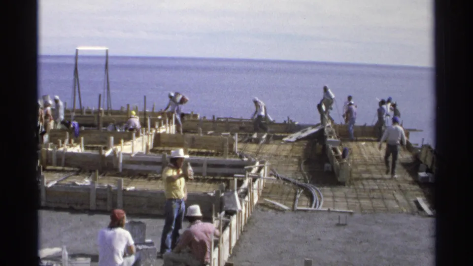 Workers on a coastal construction platform handle materials around a grid of forms and reinforcement in Guaymas, Mexico, 1975.