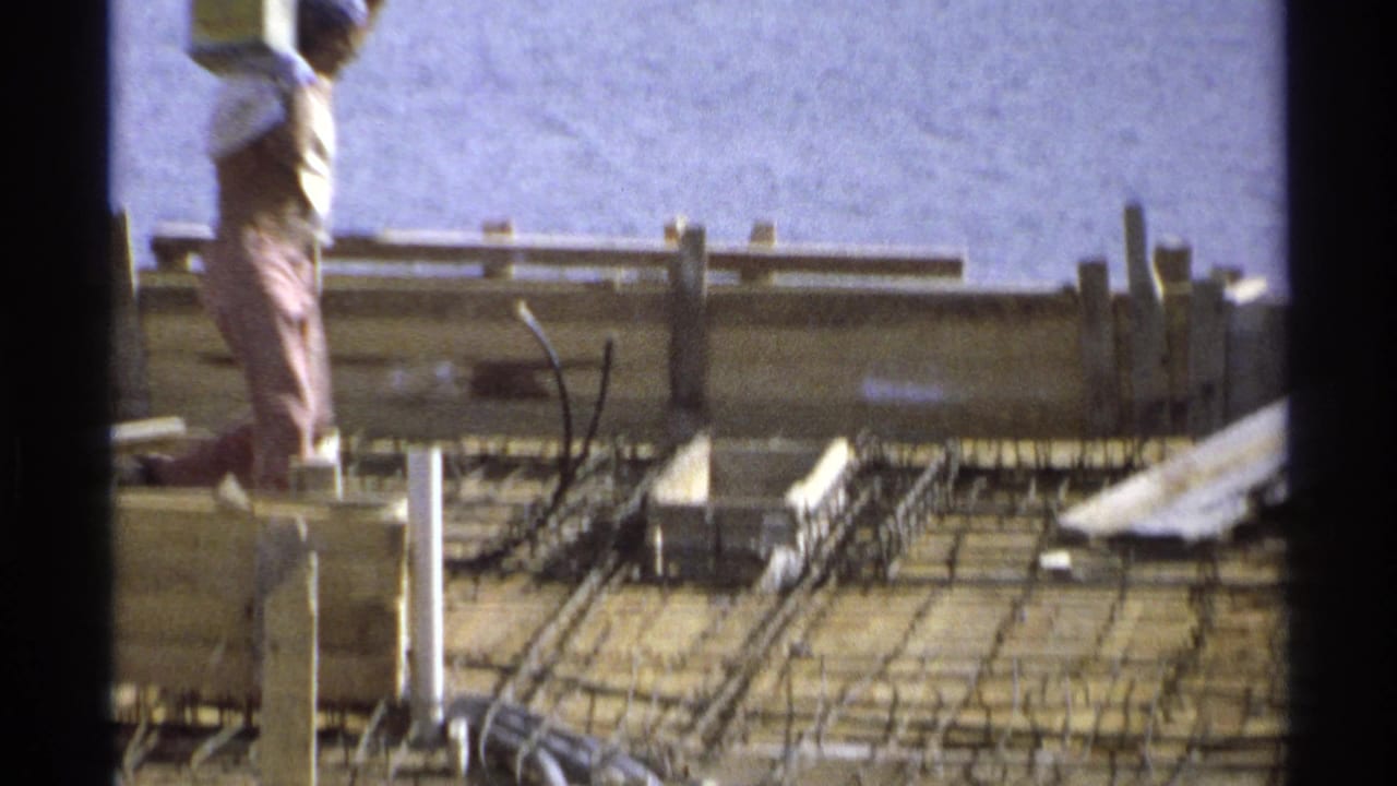 Worker standing on timber formwork above rebar at a construction site.