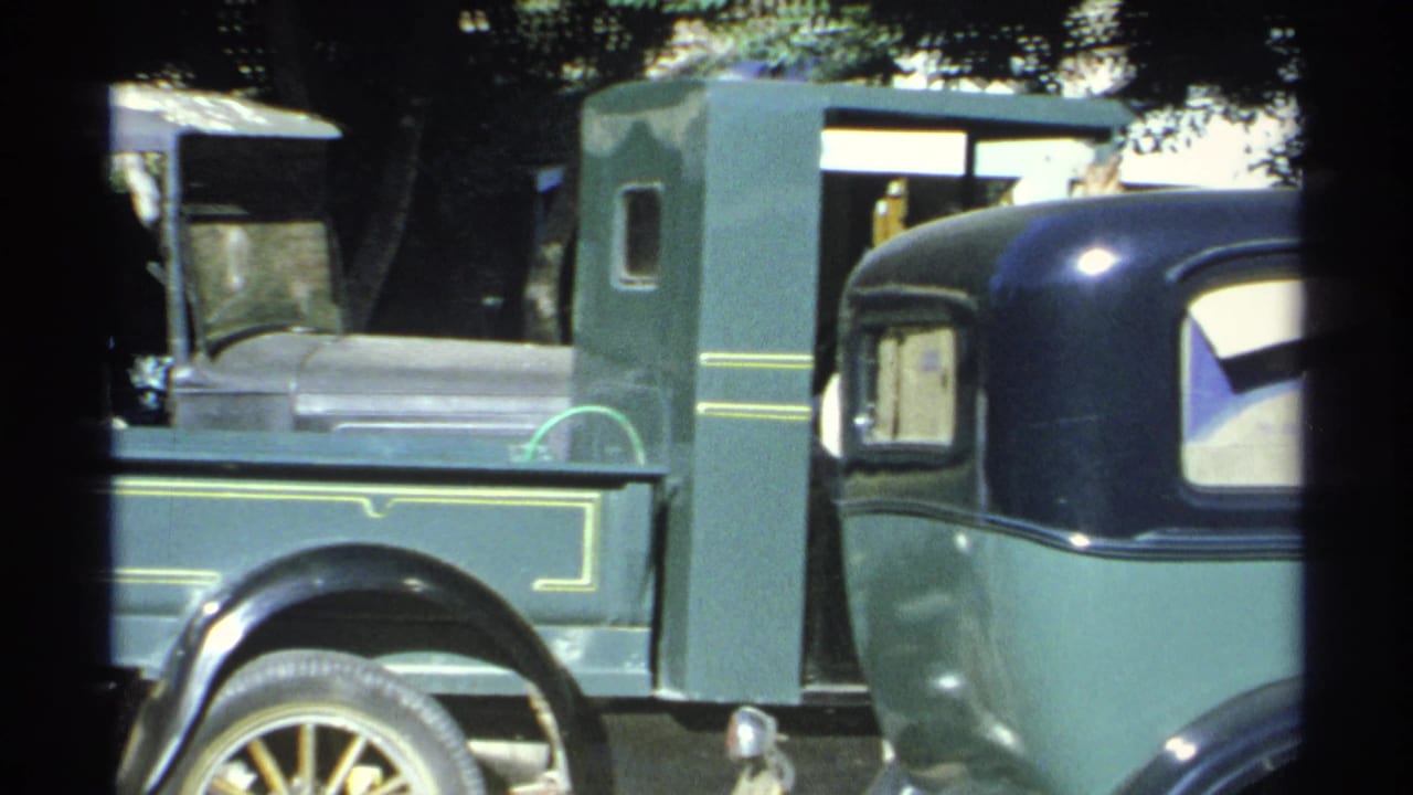 Green pickup truck fills the frame, with part of another dark-roof car at right.