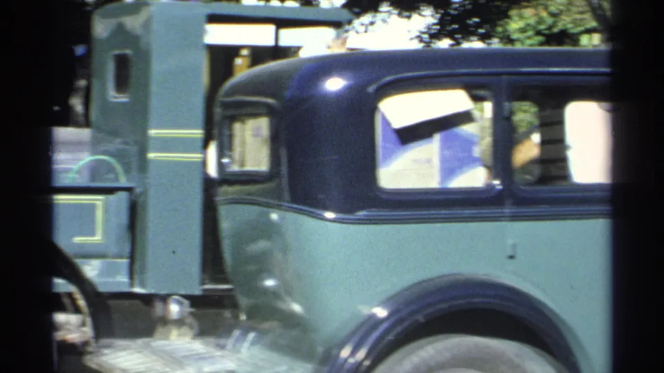 The view shifts from the green pickup to a matching green sedan with a dark roof and bright window reflections.