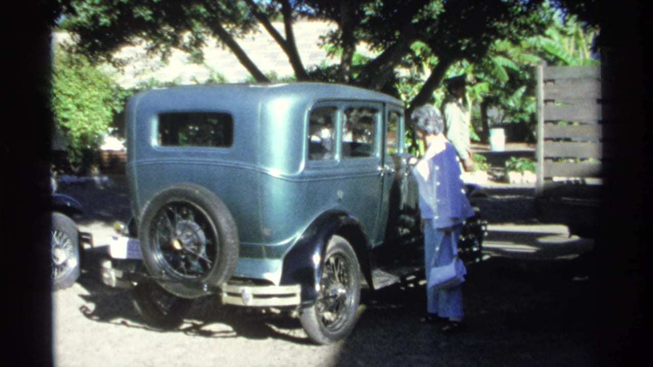 The woman in a white shirt and turquoise pants appears to examine the side of the vintage car in Guaymas, Mexico.