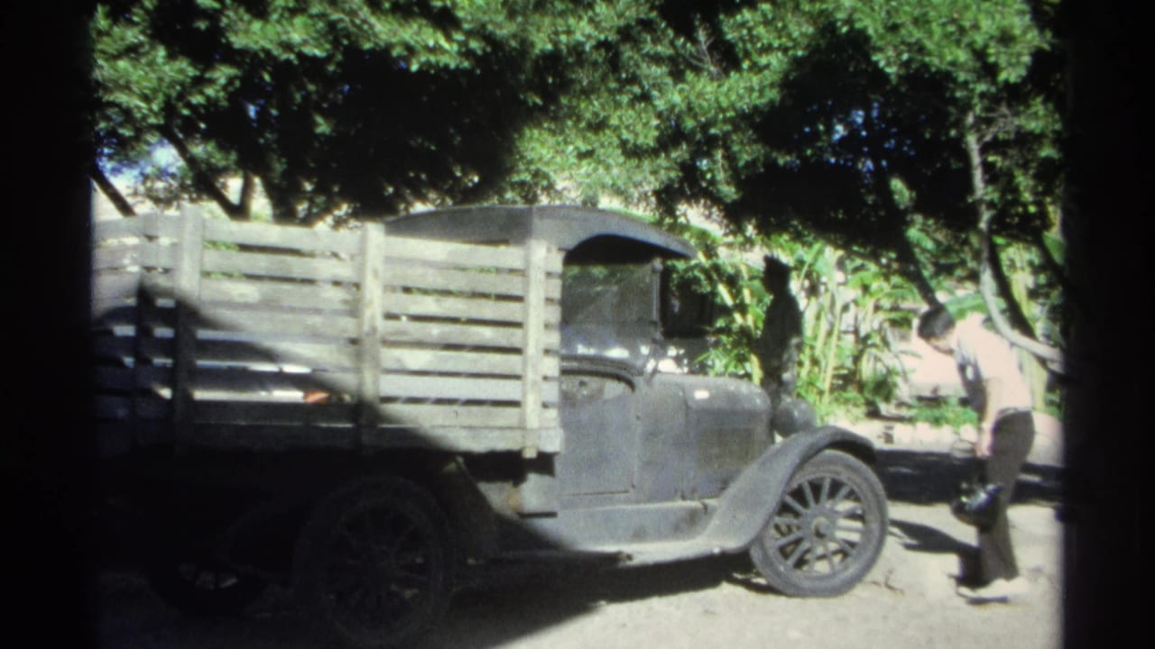 At the end of the 1975 Guaymas clip, the man walks past the front of the parked pickup as the truck remains framed under dense tree shade.
