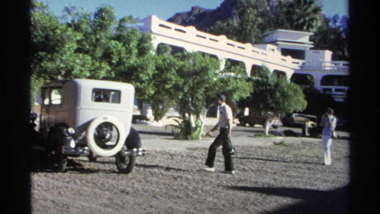 At the end of the 1975 Guaymas clip, the man walks near the white vintage car while another person stands farther across the courtyard.