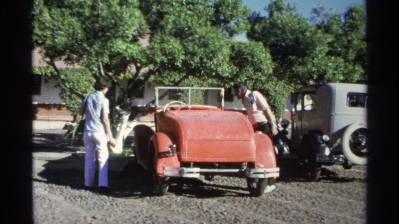 At the end of the Guaymas home-movie clip, a man leans near the red convertible as a woman stands nearby in the gravel lot.