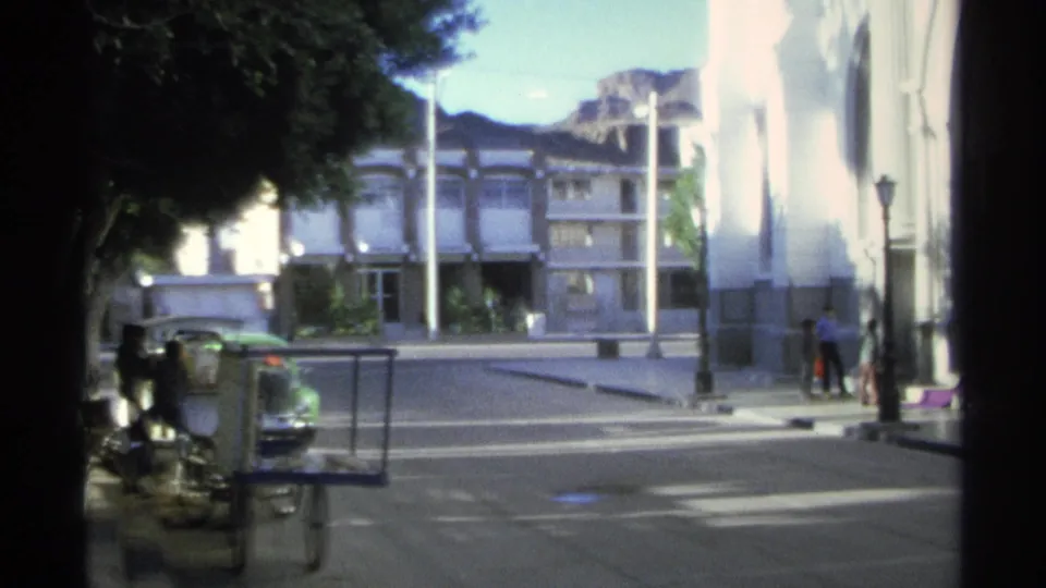 The clip ends on a Guaymas street view with buildings, trees, parked vehicles, and small adult figures near the sidewalk.
