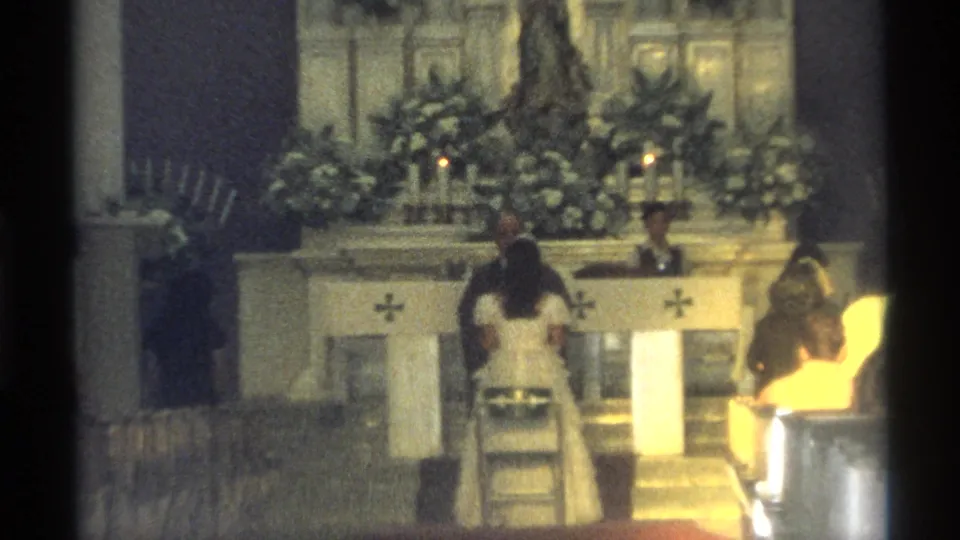 The 8mm frame shows the wedding couple facing the priest at a decorated church altar in Guaymas, Mexico.
