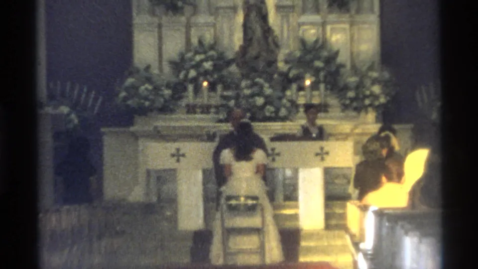 The final frame keeps the bride and groom at the decorated altar, with warm 8mm color and visible church furnishings.
