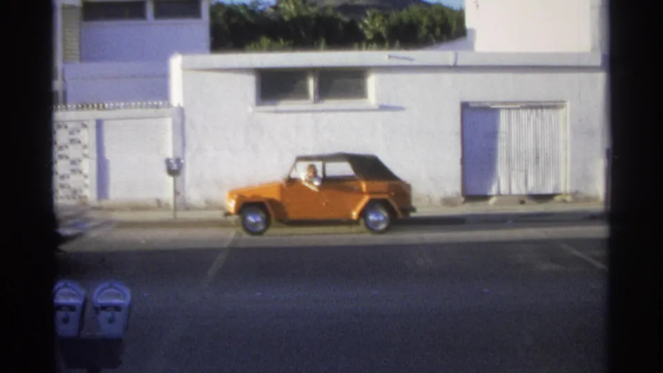 Final Guaymas frame shows the orange Volkswagen Thing beside a white stucco facade, with the driver visible through the window.